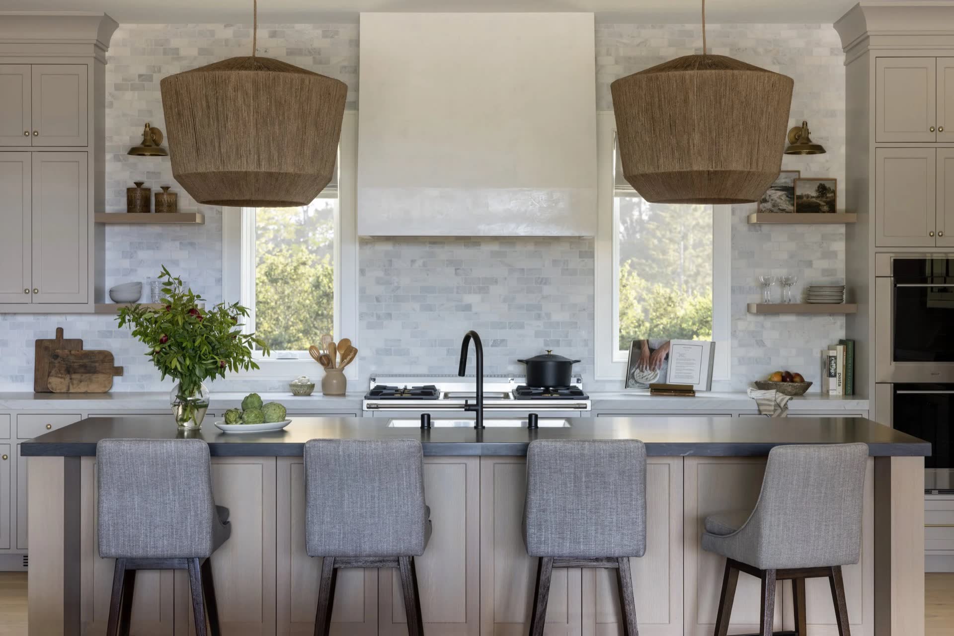 California Transitional kitchen, marble backsplash, woven pendants, and a dark stone island.