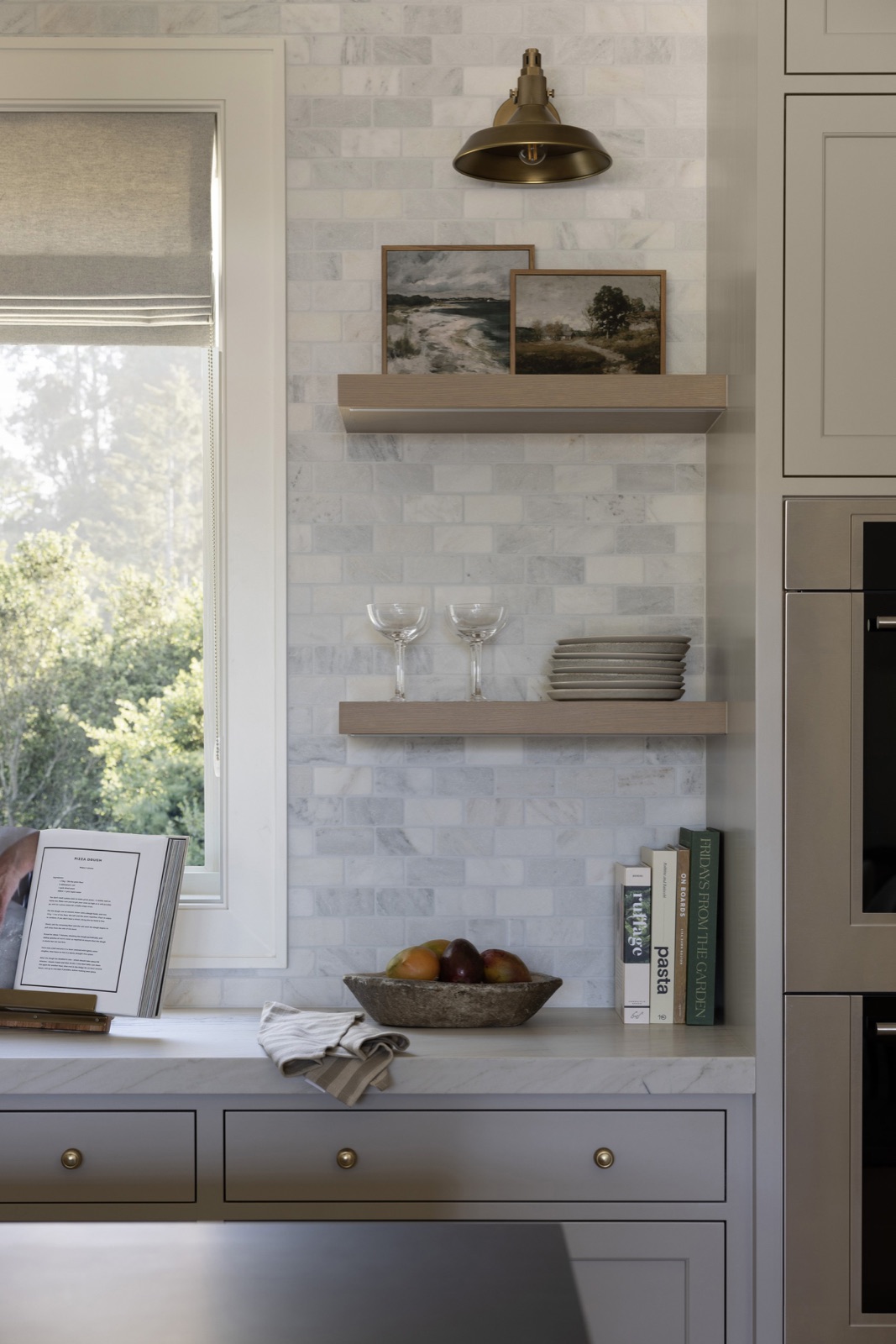 Kitchen detail, floating oak shelves, brass sconce, and marble.