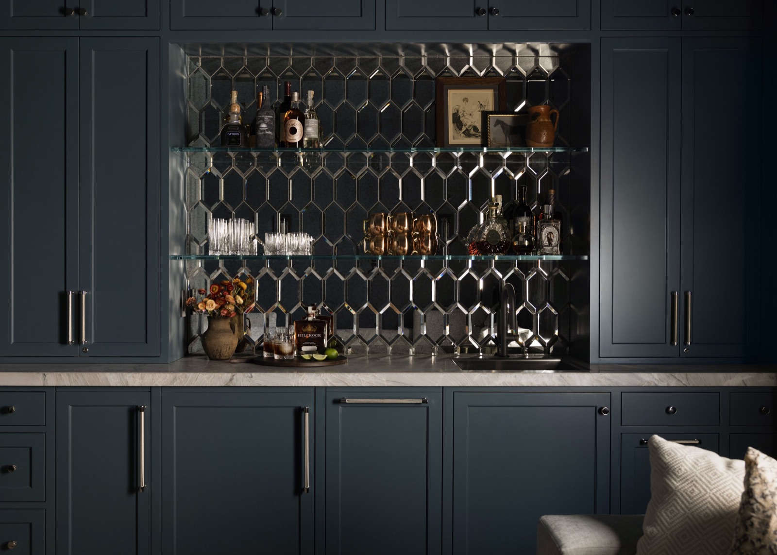 The home bar, mirrored picket-tile backsplash and glass shelves set into dark cabinetry.
