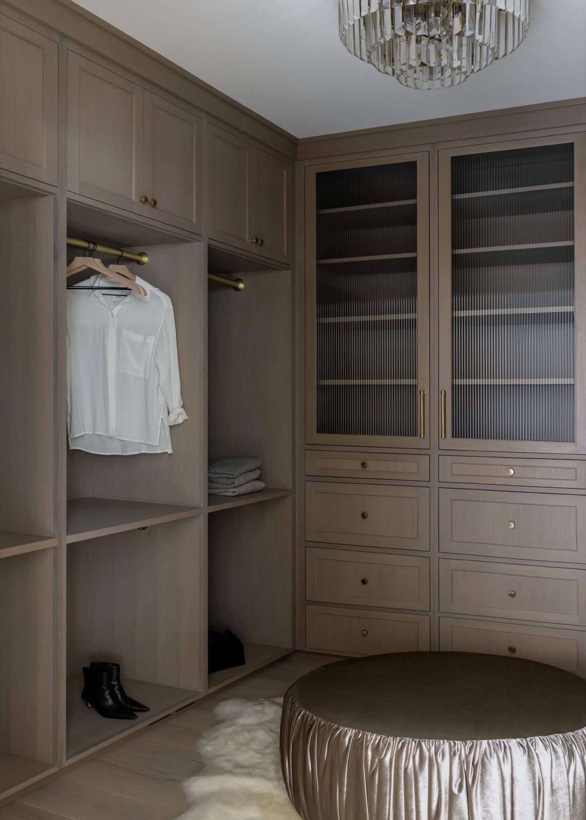 The walk-in closet, custom oak wardrobes with reeded-glass doors and a crystal chandelier.
