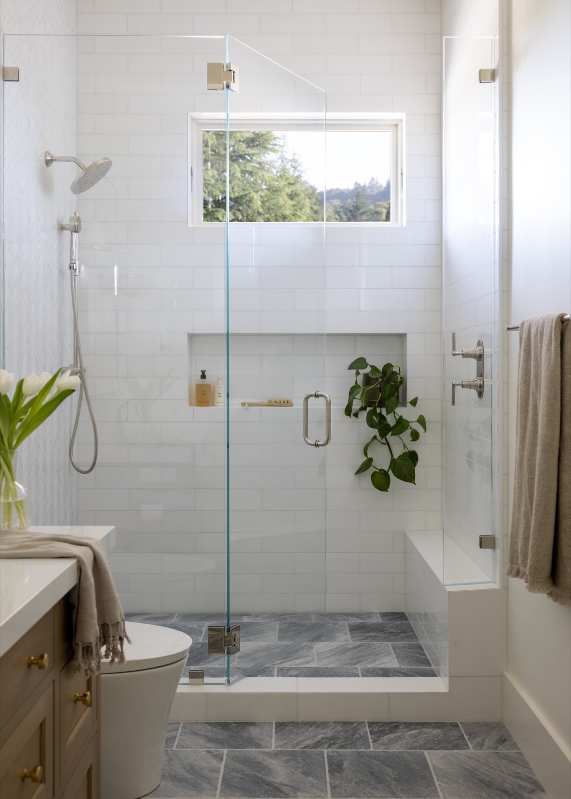 The walk-in shower, white tile with a built-in bench and bluestone floor.
