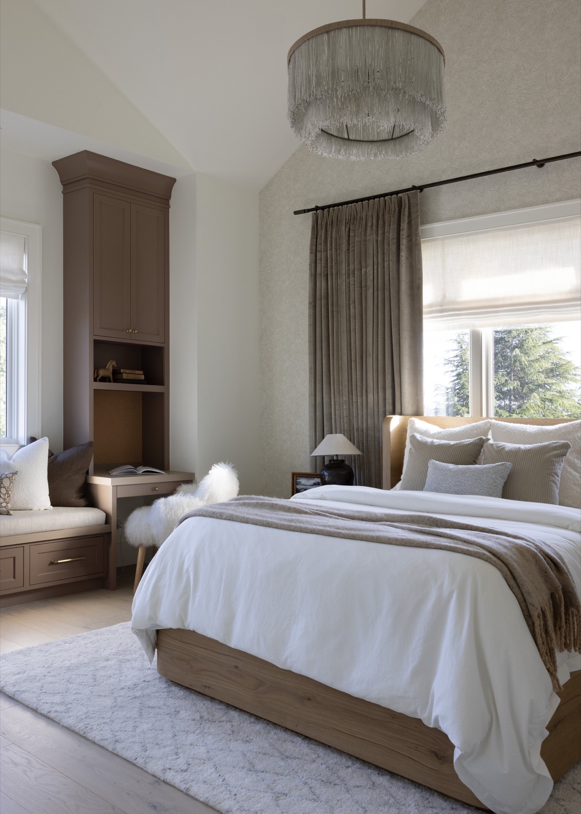 The guest suite, a fringed drum chandelier, velvet drapes, and a white oak bed.