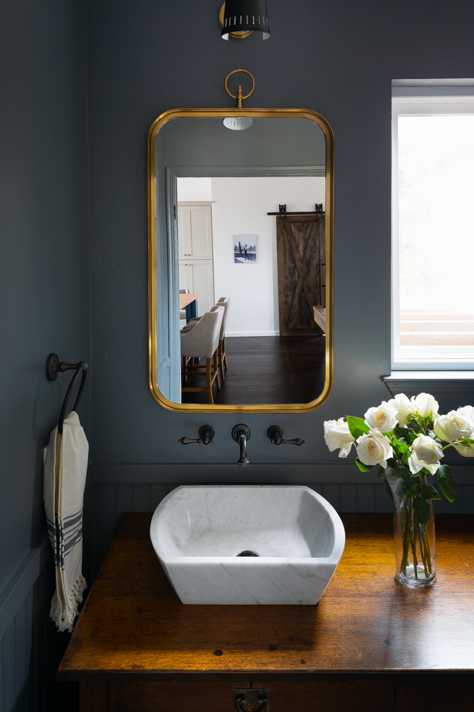 The powder bath, a marble vessel sink set on an antique dresser vanity.
