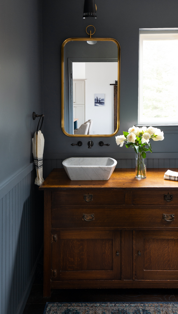 The powder bath, a brass mirror above beadboard wainscot.