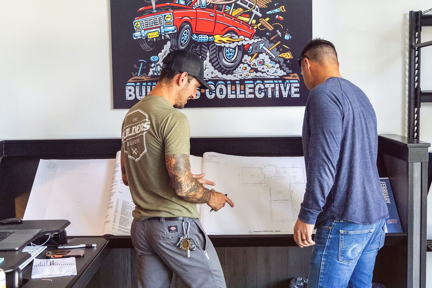 Two project leads reviewing construction drawings in the office.